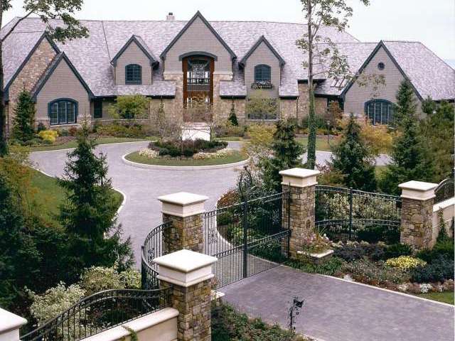 Front of house located in Bratenahl Ohio, Landscape Design includes circular drive behind gate with stone pillars.